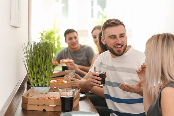 Jovens comendo pizza à mesa dentro de casa
 - Foto, Imagem