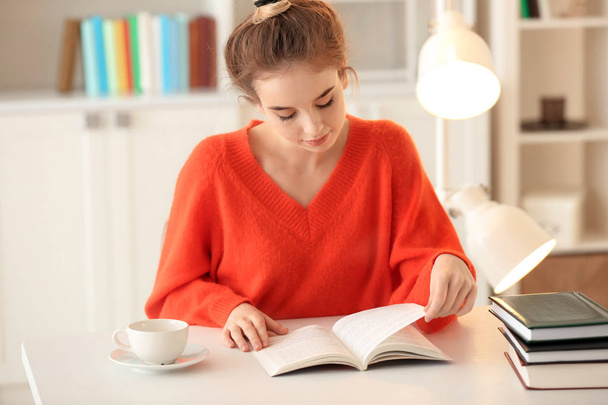 Nuori nainen lukeminen kirja pöydässä
 - Valokuva, kuva