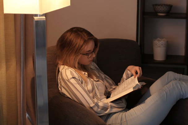 Young woman reading book at home in evening - Foto, immagini