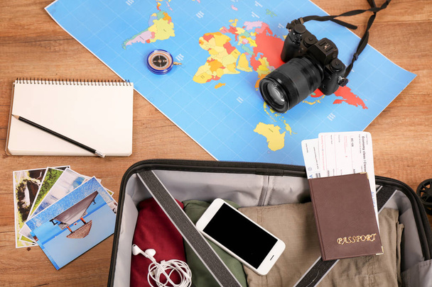 Composição com mala embalada, mapa e câmera em fundo de madeira. Conceito de viagem
 - Foto, Imagem
