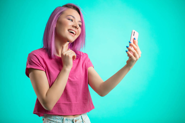 smiling woman making selfie photo on smartphone isolated on a blue background - Фото, изображение