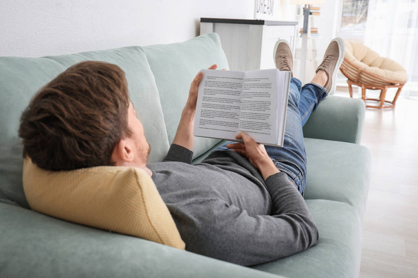 Young man reading book while resting at home - Photo, Image