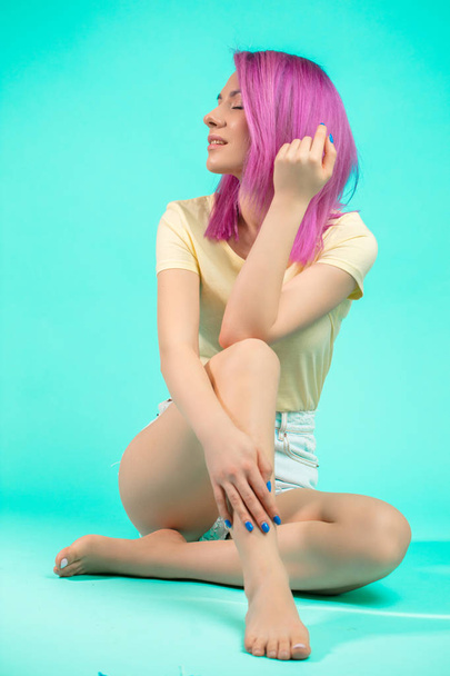 Jeune femme avec villet coiffure assis sur le sol isolé
 - Photo, image