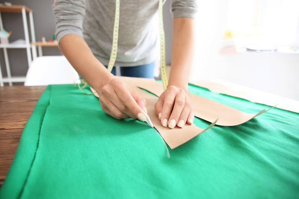Νεαρή γυναίκα ράφτης εργάζονται με ράψιμο μοτίβο στο ατελιέ - Φωτογραφία, εικόνα