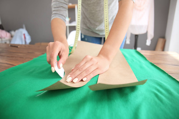 Jovem alfaiate feminino trabalhando com padrão de costura no atelier
 - Foto, Imagem