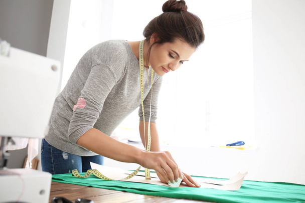 Giovane sarta donna che lavora con il modello di cucito in atelier
 - Foto, immagini