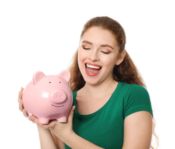 Fiatal nő malacka bank holding fehér háttér. Pénz megtakarítás fogalma - Fotó, kép