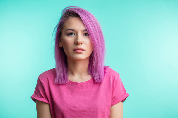 Attractive girl with pink hair, dressed in casual pink cloth on blue background. - Fotoğraf, Görsel