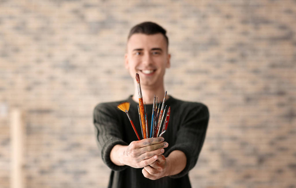 Male artist with paintbrushes in workshop - Zdjęcie, obraz