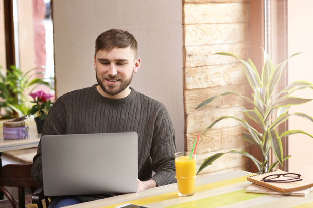 Joven freelancer con laptop trabajando en cafetería
 - Foto, Imagen