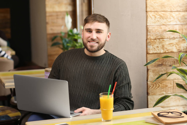 Joven freelancer con laptop trabajando en cafetería
 - Foto, Imagen