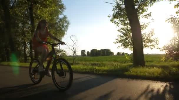 Widok z przodu z teen dziewczyna na rowerze podczas zachodu słońca - Materiał filmowy, wideo
