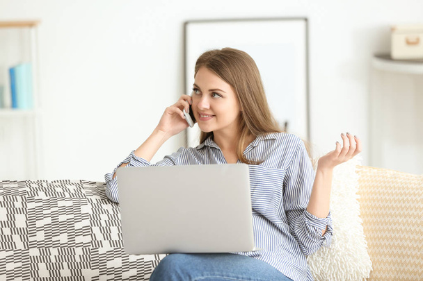 Femme freelance parler par téléphone tout en travaillant sur ordinateur portable à la maison
 - Photo, image