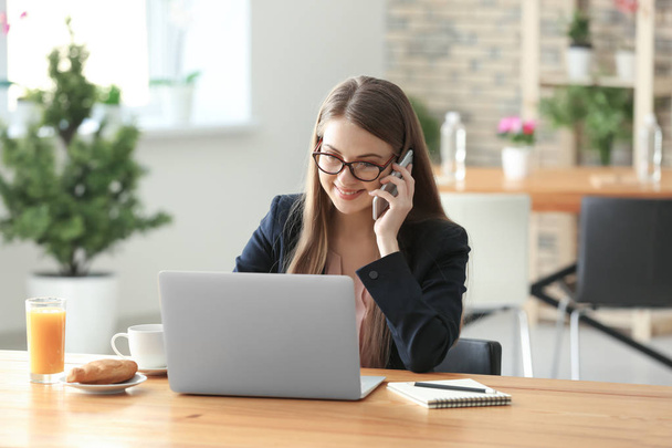Femme freelance parler par téléphone tout en travaillant sur ordinateur portable dans le café
 - Photo, image