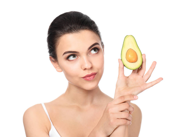 Beautiful young woman with avocado on white background - 写真・画像