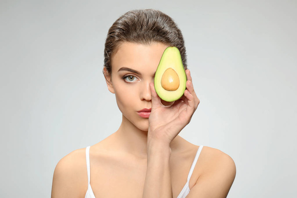 Beautiful young woman with avocado on light background - Fotografie, Obrázek