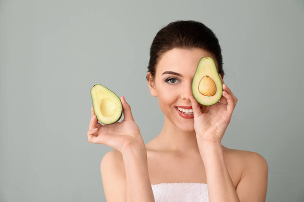 schöne junge Frau mit Avocado auf farbigem Hintergrund - Foto, Bild