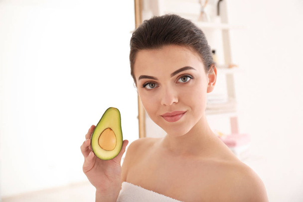Beautiful young woman with avocado in bathroom - Foto, Bild