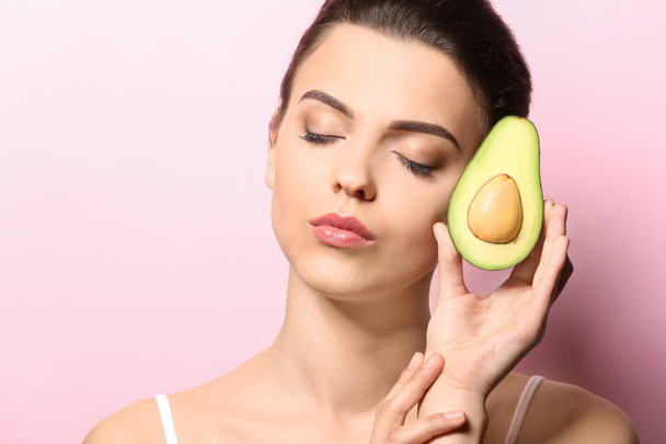 Mooie jonge vrouw met avocado op kleur achtergrond - Foto, afbeelding