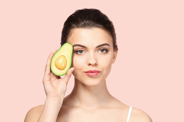 Beautiful young woman with avocado on color background - Foto, Bild