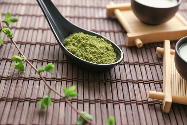 Ложка с зеленым чаем маття на бамбуковом коврике
 - Фото, изображение