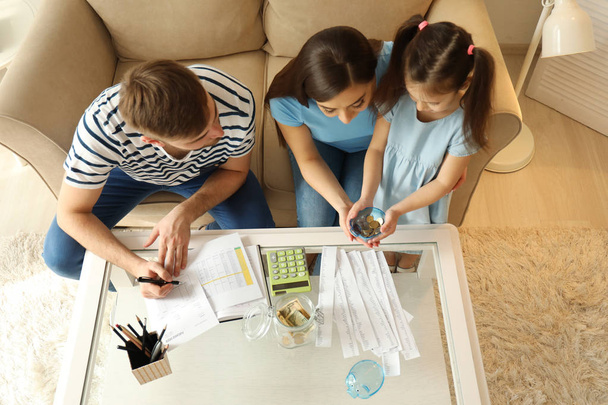 Familia con cuentas de pago, calculadora y gastos de conteo de dinero en interiores. Concepto de ahorro
 - Foto, imagen