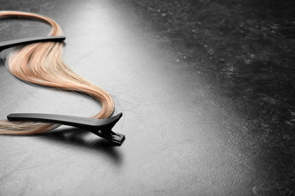 Clips with strand of blonde hair on grey background - Foto, afbeelding