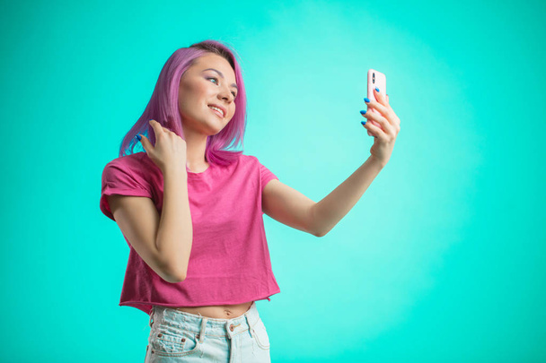 smiling woman making selfie photo on smartphone isolated on a blue background - Fotografie, Obrázek