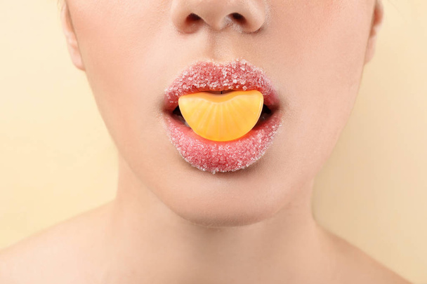 Belle jeune femme avec maquillage créatif et bonbons dans la bouche sur fond de couleur, gros plan
 - Photo, image