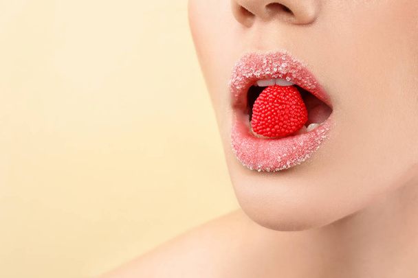 Beautiful young woman with creative makeup and candy in mouth on color background, closeup - Φωτογραφία, εικόνα