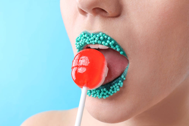 Beautiful young woman with creative makeup and lollipop on color background, closeup - Fotografie, Obrázek