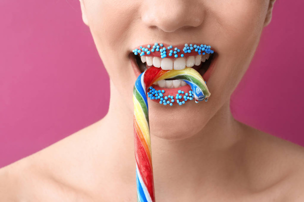 Bella giovane donna con trucco creativo e canna da zucchero su sfondo di colore, primo piano
 - Foto, immagini