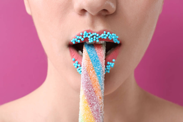 Beautiful young woman with creative makeup and candy on color background, closeup - Zdjęcie, obraz