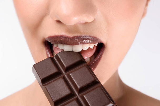 Beautiful young woman with chocolate on white background, closeup - Foto, Imagem
