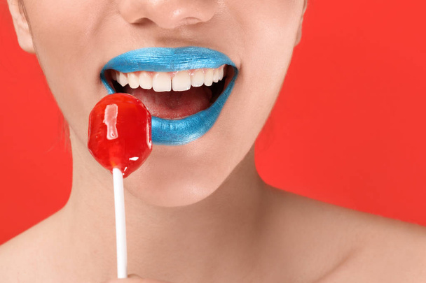 Beautiful young woman with creative makeup and lollipop on color background, closeup - Foto, imagen