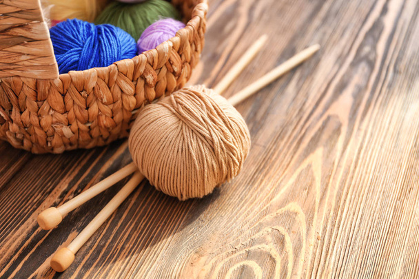 Cesta de vime com fios de tricô e agulhas na mesa
 - Foto, Imagem