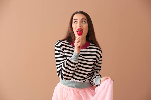 Attractive young woman with lollipop on color background - Fotoğraf, Görsel