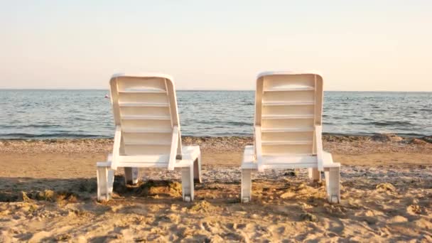 Twee chaise-longues op het strand. - Video
