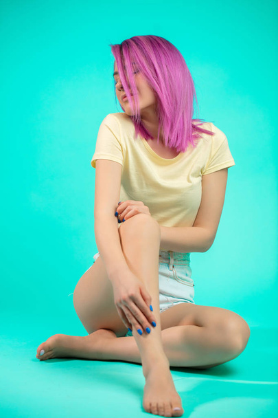 Young woman with villet hairstyle sitting on the floor isolated - Photo, image
