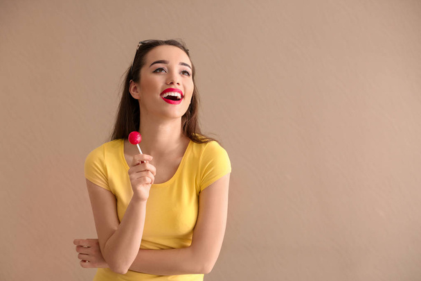 Atrakcyjna, młoda kobieta z lollipop na kolor tła - Zdjęcie, obraz