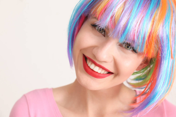 Beautiful young woman with colorful hair on light background - Photo, Image