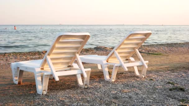 Two plastic chaise longues on seashore. - Footage, Video