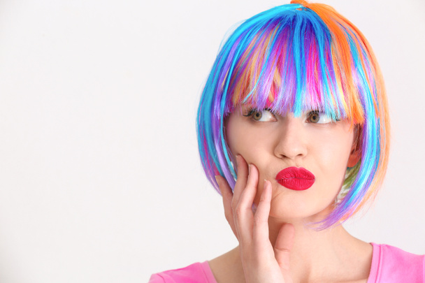 Эмоциональная молодая женщина с красочными волосами на светлом фоне
 - Фото, изображение