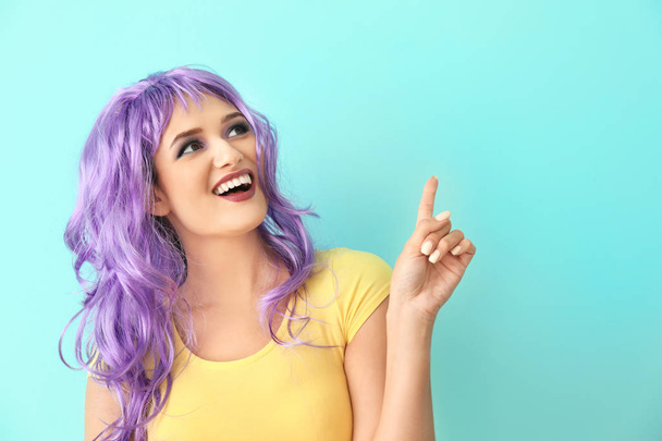 Extravagant young woman with raised index finger on color background - Foto, afbeelding