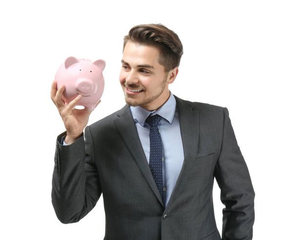 Young businessman holding piggy bank on white background. Savings money concept - Photo, Image