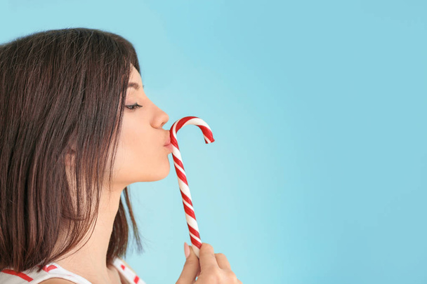 Beautiful young woman with candy cane on color background - Photo, Image