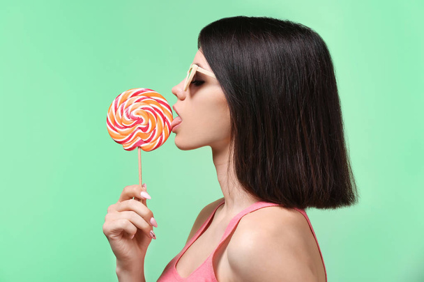 Beautiful young woman with lollipop on color background - Foto, immagini