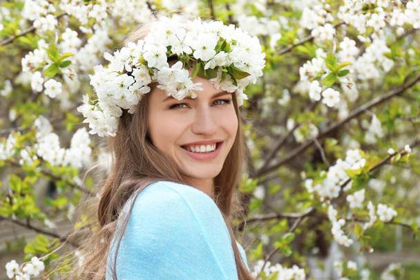Όμορφη νεαρή γυναίκα που φοράει λουλούδι στεφάνι σε εξωτερικούς χώρους ημέρα της άνοιξης - Φωτογραφία, εικόνα