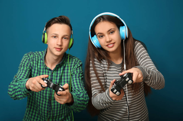 Teenagers with gamepads on color background - Photo, Image