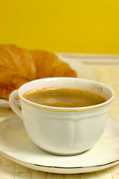 Una taza de café con croissant en el fondo
 - Foto, Imagen